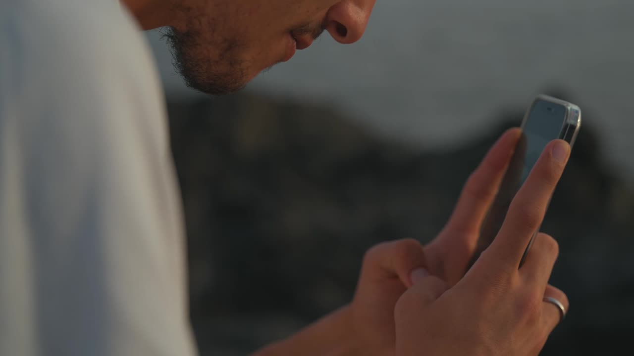 A hand raising a phone to keep one frame of the sea
