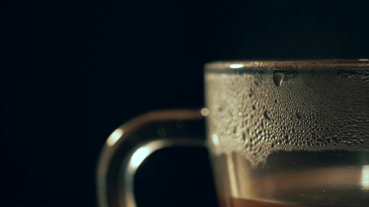 A glass of tea sweating in the dark